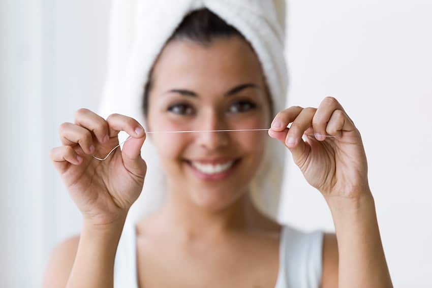 young woman prepares to floss her teeth