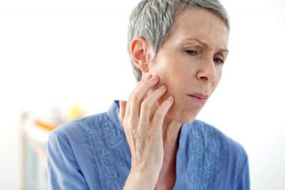 senior woman holding her jaw in pain