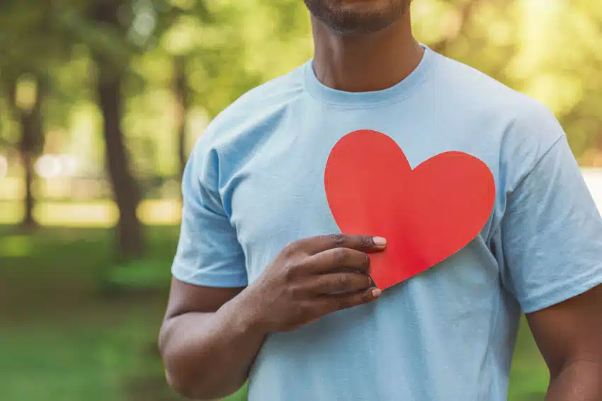 adult man holding a paper heart over his chest