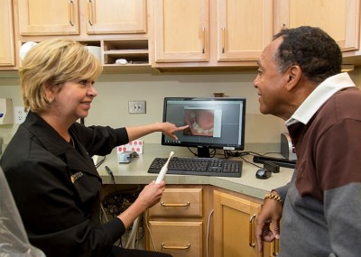 Dental assistant educating patient on preventative dentistry with intraoral camera