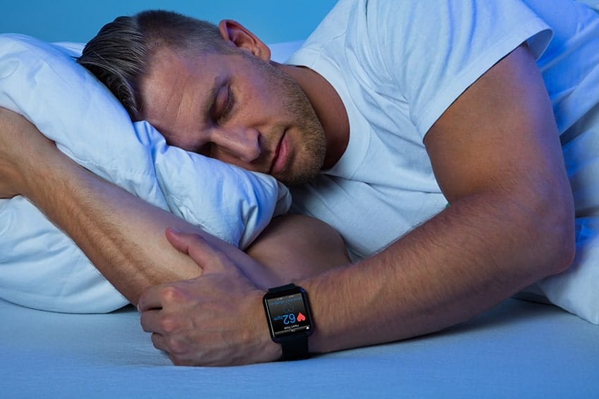 man sleeping peacefully, laying on his side wearing smart watch