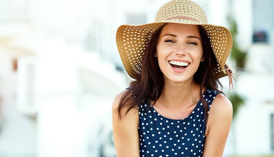 young woman in cute sun hat laughs while enjoying the outdoors