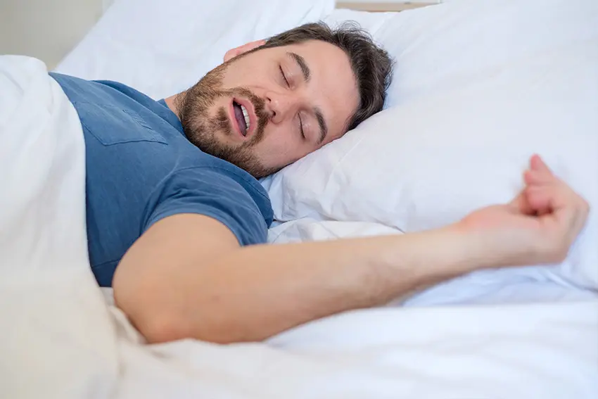 man snoring while laying on his back in bed