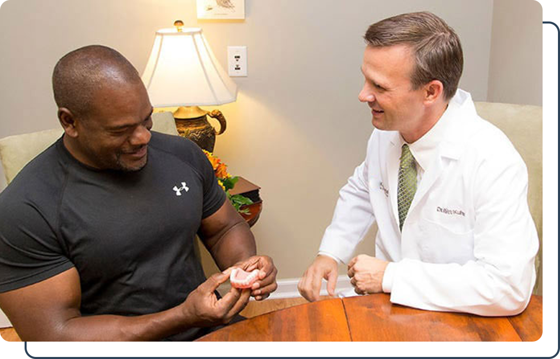 Dr. Kuhn discussing benefits of dental implatns with patient Dr. Ritt Kuhn explaining tooth replacement options with a patient